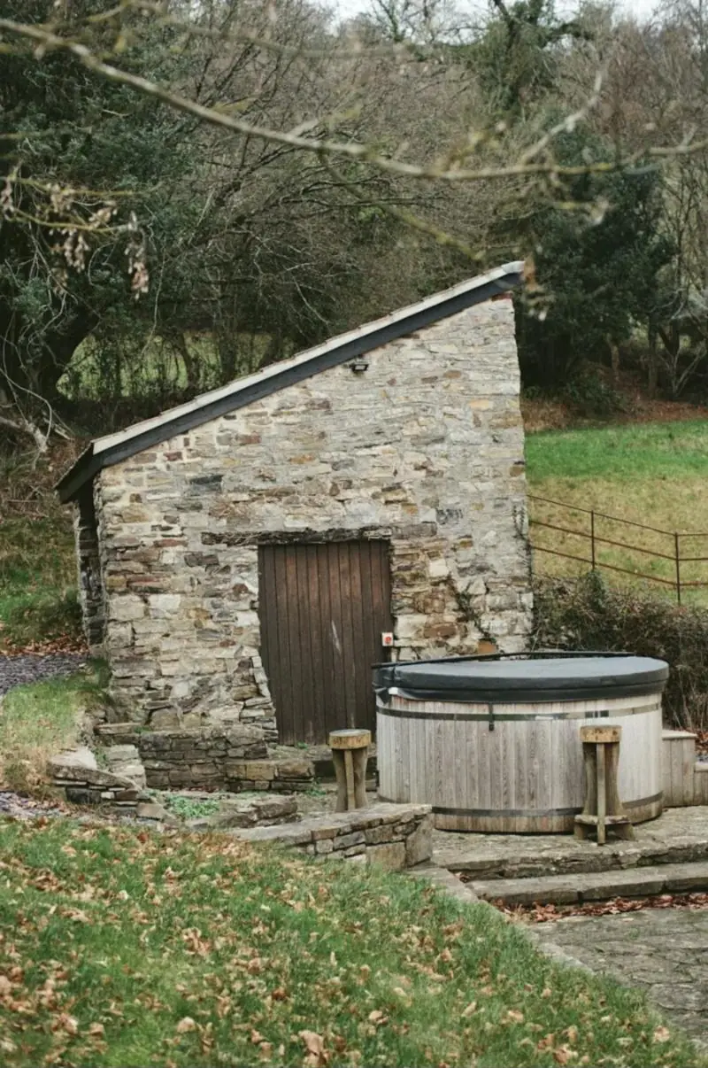 Bain nordique devant une petite dépendance en pierre, dans un jardin en pente