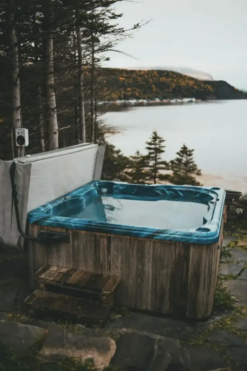 Spa avec habillage bois au bord d'un lac, entouré de sapins
